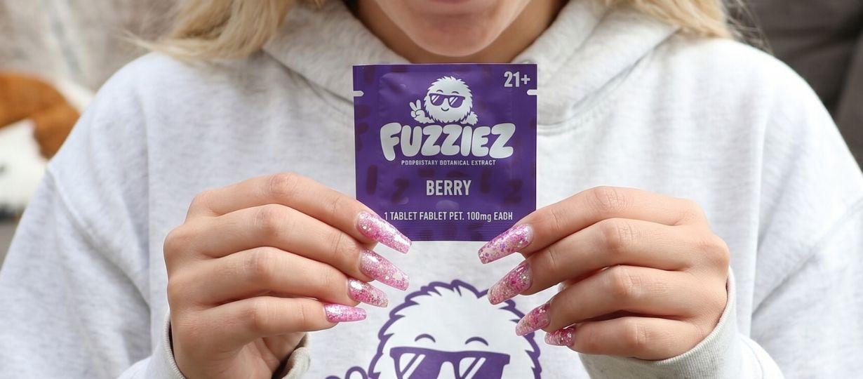 Is Fuzziez Legal in All 50 States? Person holding a Fuzziez Berry sachet — 100mg proprietary botanical extract, 21+ only